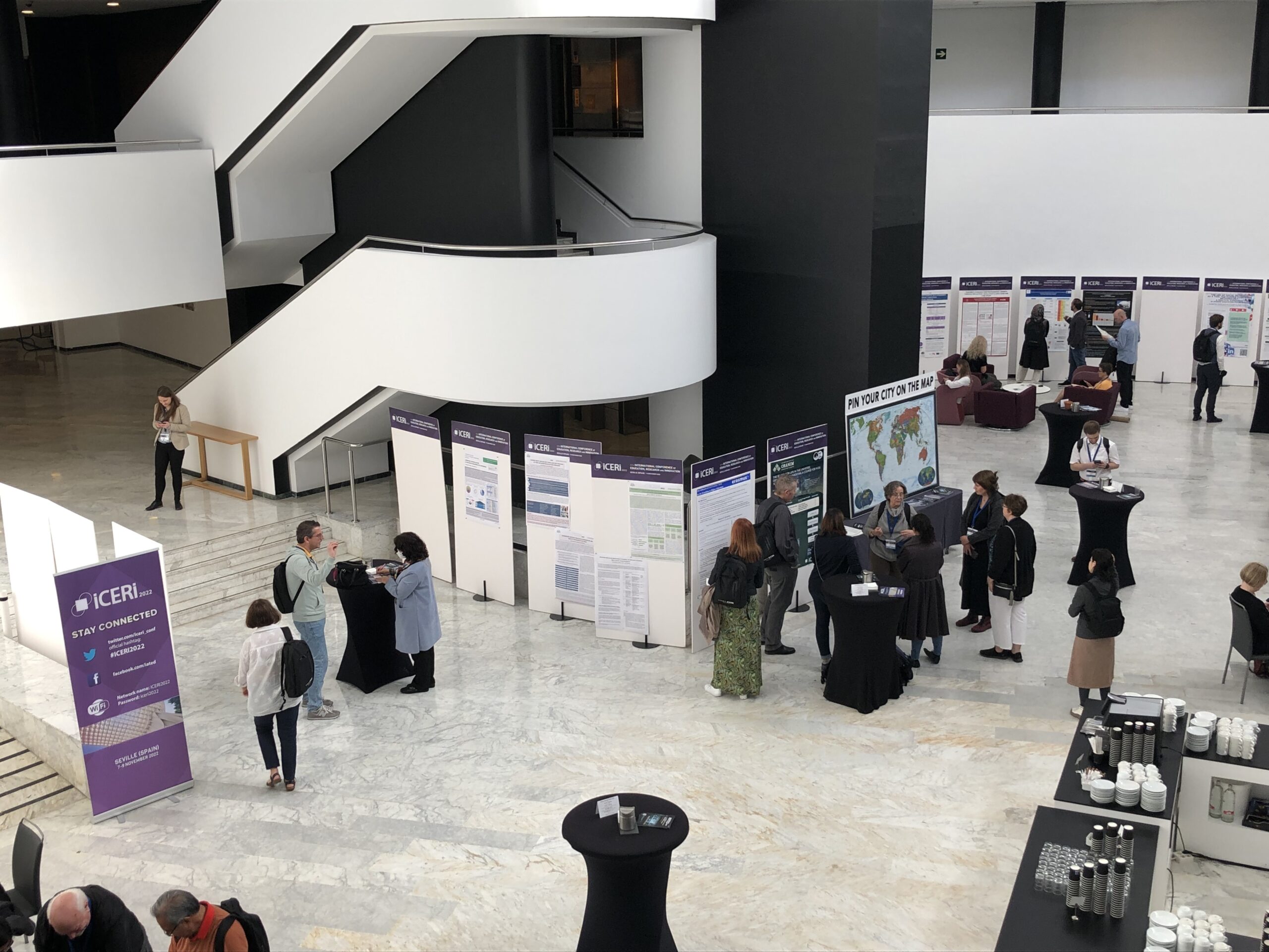 A staircase inside a conference center and some delegates looking at posters.